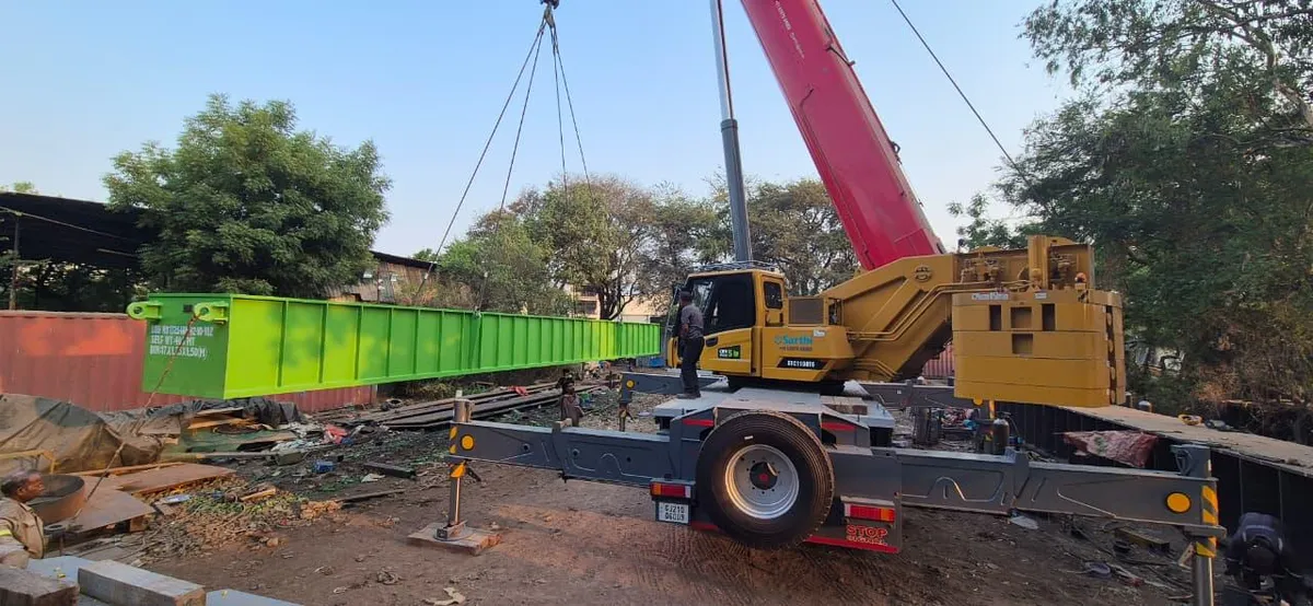 Long fabricated members handled by crane and prepared for project movement.